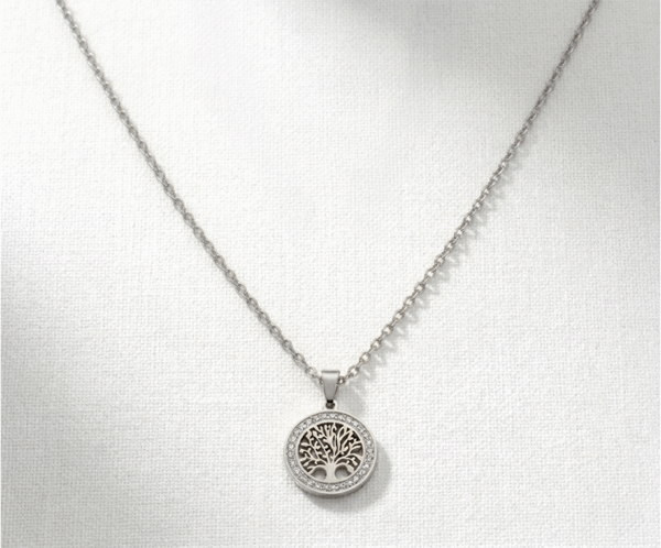 El Collar Árbol Crystal Circle Silver es una pieza de magnetismo puro que simboliza la vida y el renacimiento. Presenta un medallón central con el Árbol de la Vida, realzado por un círculo de cristales brillantes que aportan luz y sofisticación. Fabricado en acero quirúrgico, ofrece un acabado plateado impecable y duradero para un estilo con propósito.
