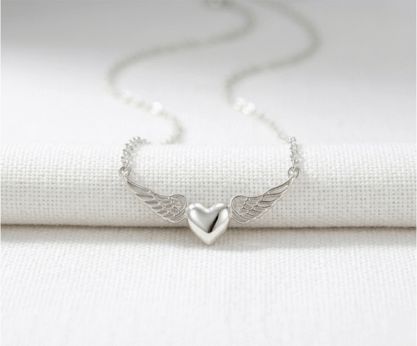 Este collar minimalista plateado simboliza un amor protector que trasciende lo terrenal. Presenta un delicado colgante de corazón pulido flanqueado por alas de ángel detalladas, creando una silueta etérea y atemporal. Fabricado en acero quirúrgico de alta calidad, es una joya resistente y llena de significado, perfecta para llevar como amuleto diario o como un regalo profundamente emocional.