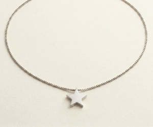 El Collar Estrella Minimal Silver es una joya de elegancia pura y moderna. Presenta un dije de estrella sólida con acabado pulido espejo que se desliza delicadamente sobre una sofisticada cadena tipo serpiente. Fabricado en acero quirúrgico de alta calidad, es una pieza atemporal y resistente, diseñada para capturar la luz con un estilo sutil y sofisticado.