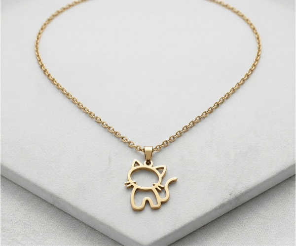 El Collar Michi Minimal Dorado es una joya terna y minimalista con un radiante acabado dorado. Destaca por su encantador dije calado con la silueta de un pequeño gato sentado, detallando sus bigotes y una graciosa cola curvada. Fabricado en acero quirúrgico, es el accesorio perfecto para amantes de los animales.
