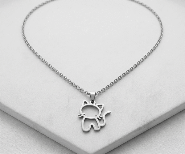 Collar Michi Minimal Plateado _E108 El Collar Michi Minimal Plateado es una joya tierna y minimalista con un impecable acabado plateado brillante. Destaca por su encantador dije calado con la silueta de un pequeño gato sentado, detallando sus bigotes y una graciosa cola curvada. Fabricado en acero quirúrgico, es el accesorio perfecto para amantes de los animales.