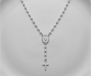 El Collar Rosario Perlas & Silver es una joya mística que fusiona espiritualidad y elegancia contemporánea con un impecable acabado plateado. Destaca por su delicada cadena intercalada con perlas blancas brillantes, que fluyen hacia una medalla central ovalada y una cruz pulida. Fabricado en acero quirúrgico, es un amuleto sofisticado y duradero.
