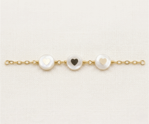 La Pulsera Aros con Corazón es una joya de elegancia atemporal que destaca por su exquisito acabado dorado. Presenta tres medallones circulares de nácar natural con delicados corazones en su centro, unidos por una refinada cadena de eslabones. Fabricada en acero quirúrgico, combina romanticismo y luz con un estilo artesanal único.