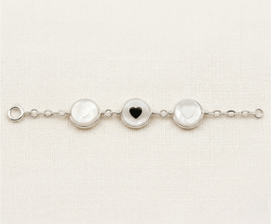 La Pulsera Aros con Corazón es una pieza de exquisita dulzura y acabado artesanal con un brillo plateado impecable. Destaca por tres medallones circulares de nácar natural que albergan delicados corazones en su centro, unidos por una elegante cadena de eslabones. Fabricada en acero quirúrgico, combina romanticismo y luz con un estilo atemporal.