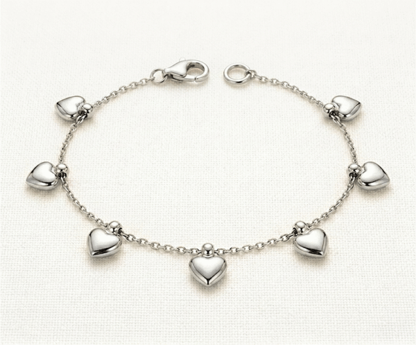 Pulsera Cascada de Corazones _A132 La Pulsera Cascada de Corazones es una pieza de exquisita delicadeza y encanto romántico con un acabado plateado brillante. Presenta siete dijes de corazón con volumen tridimensional que caen con suavidad sobre una fina cadena de eslabones. Fabricada en acero quirúrgico, es el accesorio perfecto para un estilo femenino, moderno y sofisticado.