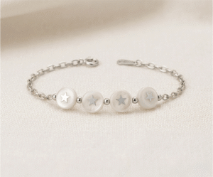 La Pulsera Círculos Nacarados es una joya de elegancia atemporal y brillo orgánico con un acabado plateado impecable. Destaca por sus cuatro medallones circulares de nácar natural que incluyen estrellas plateadas en su centro, unidos por una refinada cadena de eslabones. Fabricada en acero quirúrgico, combina sofisticación y luz con un estilo único.