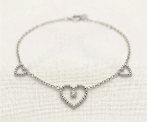 La Pulsera Corazón Central es una joya de elegancia sublime con un acabado plateado brillante. Presenta un corazón central calado con un cristal solitario engastado, escoltado por dos corazones laterales de diseño perlado sobre una delicada cadena de eslabones. Fabricada en acero quirúrgico, es el accesorio perfecto para un estilo romántico y sofisticado.