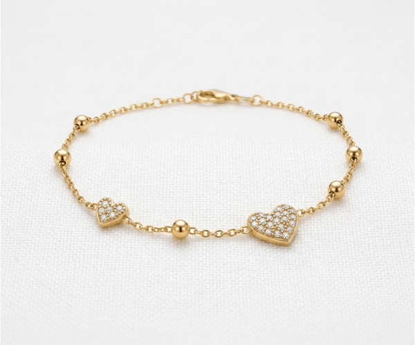 La Pulsera Corazón de Cristales es una pieza deslumbrante que combina romanticismo y lujo. Presenta dos dijes de corazón con un exquisito pavé de cristales brillantes, intercalados con esferas pulidas sobre una delicada cadena dorada. Fabricada en acero quirúrgico, es la joya perfecta para quienes buscan un brillo sofisticado y duradero.
