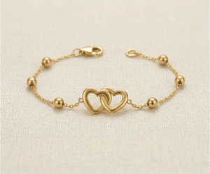 La Pulsera Corazones Entrelazados es una joya llena de significado y elegancia. Presenta un dije central de dos corazones calados íntimamente unidos, acompañados por delicadas esferas pulidas en una cadena de eslabones dorados. Fabricada en acero quirúrgico, es el accesorio perfecto para simbolizar la unión eterna con un estilo sofisticado y atemporal.