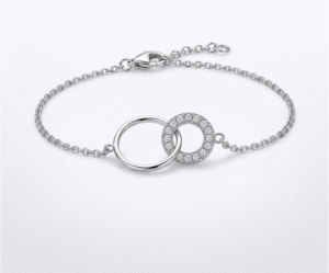 La Pulsera Dúo de Aros es un símbolo de unión eterna y sofisticación moderna. Presenta dos anillos entrelazados: uno de acabado pulido liso y otro adornado con un pavé de cristales brillantes que capturan la luz. Fabricada en acero quirúrgico plateado, es la pieza ideal para quienes buscan un accesorio significativo con un brillo lujoso y duradero.