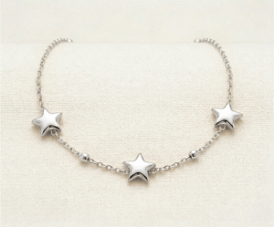 La Pulsera Estrella Fugaz es una pieza mágica que captura la esencia del cosmos con un brillo plateado excepcional. Presenta tres estrellas de cinco puntas con un suave relieve tridimensional, acompañadas de delicadas esferas pulidas. Fabricada en acero quirúrgico, es una joya resistente y sofisticada que simboliza sueños y deseos con elegancia minimalista.