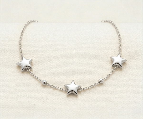 La Pulsera Estrella Fugaz es una pieza mágica que captura la esencia del cosmos con un brillo plateado excepcional. Presenta tres estrellas de cinco puntas con un suave relieve tridimensional, acompañadas de delicadas esferas pulidas. Fabricada en acero quirúrgico, es una joya resistente y sofisticada que simboliza sueños y deseos con elegancia minimalista.