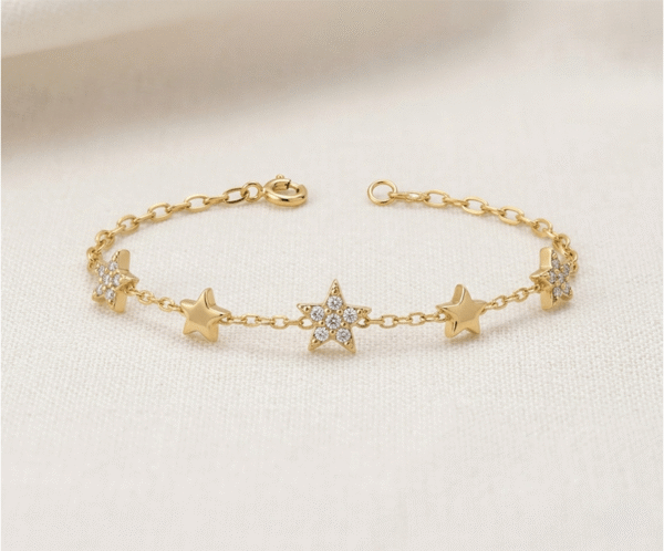 La Pulsera Estrellas de Cristales es una pieza radiante con un sofisticado acabado dorado que captura la esencia del cosmos. Presenta tres estrellas centrales con un brillante pavé de cristales, escoltadas por dos estrellas lisas sobre una delicada cadena de eslabones. Fabricada en acero quirúrgico, combina elegancia y luz con distinción.