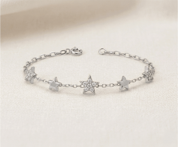 La Pulsera Estrellas de Cristales es una joya radiante que captura la esencia de una noche despejada en un acabado plateado impecable. Presenta tres estrellas centrales con un brillante pavé de cristales, escoltadas por dos estrellas lisas con acabado pulido sobre una delicada cadena. Fabricada en acero quirúrgico, combina elegancia y luz con sofisticación.