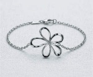 La Pulsera Flor Silvestre es una joya que captura la frescura y delicadeza de la naturaleza. Presenta un dije central de una flor con pétalos calados de trazos fluidos y un acabado pulido espejo que deslumbra. Fabricada en acero quirúrgico plateado, es una pieza ligera y sofisticada, ideal para realzar tu feminidad con elegancia.