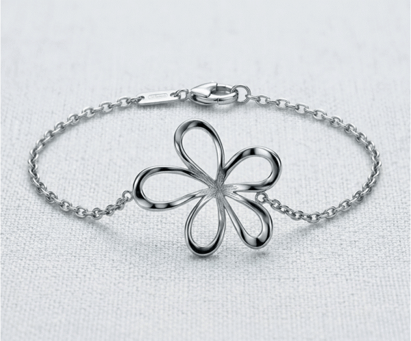 La Pulsera Flor Silvestre es una joya que captura la frescura y delicadeza de la naturaleza. Presenta un dije central de una flor con pétalos calados de trazos fluidos y un acabado pulido espejo que deslumbra. Fabricada en acero quirúrgico plateado, es una pieza ligera y sofisticada, ideal para realzar tu feminidad con elegancia.