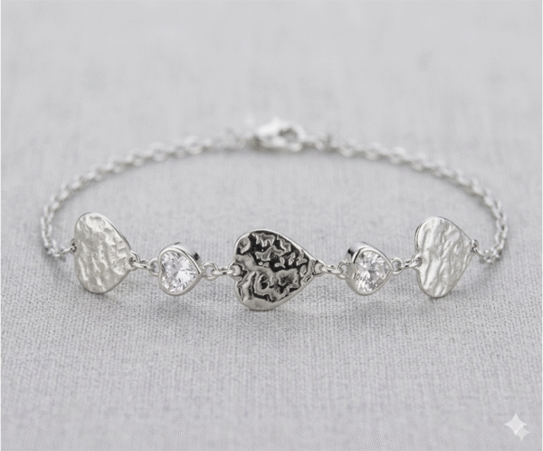 La Pulsera Gotas de Cristal es una pieza de diseño artístico y acabado plateado envejecido que destaca por su carácter único. Combina tres dijes de corazón con una textura orgánica martillada e irregular, intercalados con dos cristales brillantes facetados de gran pureza. Fabricada en acero quirúrgico, ofrece un estilo bohemio y sofisticado.