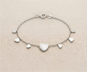 La Pulsera Lluvia de Corazones es una pieza de exquisita delicadeza y encanto romántico con un acabado plateado brillante. Presenta un corazón central con textura martillada artesanal, rodeado por pequeños dijes lisos que caen en cascada sobre una fina cadena. Fabricada en acero quirúrgico, es el accesorio perfecto para un estilo femenino.
