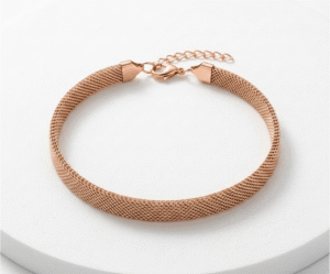 La Pulsera Malla Pink Gold es una joya sofisticada de diseño plano y tubular con un romántico acabado en oro rosa brillante. Destaca por su elegante tejido de malla flexible, que imita una textura sedosa muy favorecedora. Fabricada en acero quirúrgico, incorpora un cierre de mosquetón con cadena ajustable para un calce perfecto.