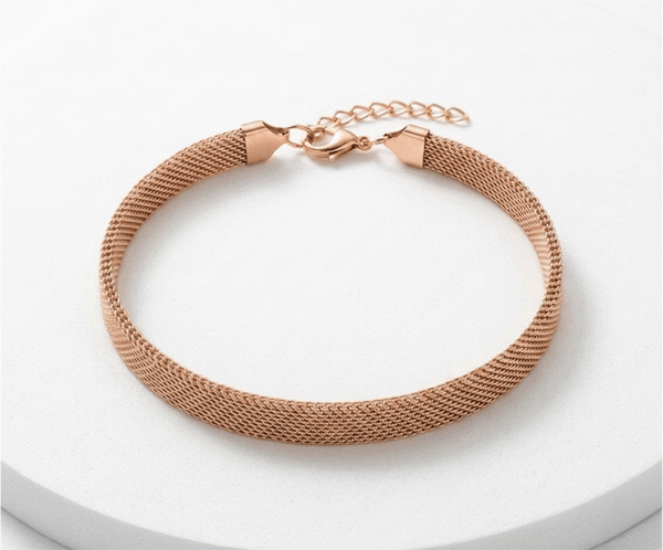La Pulsera Malla Pink Gold es una joya sofisticada de diseño plano y tubular con un romántico acabado en oro rosa brillante. Destaca por su elegante tejido de malla flexible, que imita una textura sedosa muy favorecedora. Fabricada en acero quirúrgico, incorpora un cierre de mosquetón con cadena ajustable para un calce perfecto.