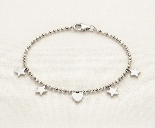 La Pulsera Mix Galáctico es una joya mística y moderna con un acabado plateado brillante. Presenta una cadena de cuentas esféricas uniformes adornada con cuatro estrellas lisas y un corazón central. Fabricada en acero quirúrgico, esta pieza combina la inspiración celestial con un diseño minimalista, siendo un accesorio versátil, duradero y lleno de elegancia contemporánea.