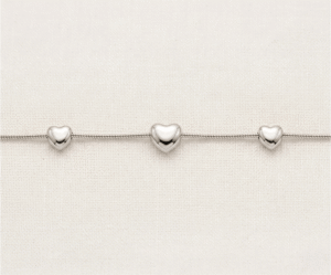La Pulsera Trio de Corazones es una pieza de elegancia minimalista con un impecable acabado plateado. Presenta tres corazones con volumen y relieve suave, integrados armoniosamente en una sofisticada cadena de estilo serpiente. Fabricada en acero quirúrgico, es una joya moderna y versátil, ideal para simbolizar vínculos especiales con una discreción sofisticada y duradera.