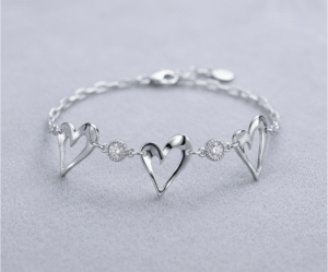 La Pulsera Triple Corazón es una joya que destila romance y modernidad. Presenta tres elegantes siluetas de corazones calados con acabado pulido, intercalados con brillantes cristales engastados que capturan la luz. Fabricada en acero quirúrgico de alta calidad, es una pieza sofisticada y resistente, ideal para simbolizar vínculos especiales con un estilo ligero y refinado.
